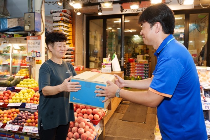 CJ대한통운 택배기사가 오산 오색시장 과일가게 상인이 접수한 택배 상자를 집화하고 있다. ⓒ CJ대한통운