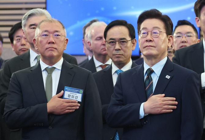 이재명 대통령이 지난 2월27일 전북 군산새만금컨벤션센터에서 열린 새만금 로봇·수소·AI 시티 투자협약식에서 국민의례를 하고 있다. 왼쪽은 정의선 현대차그룹 회장. ⓒ 연합뉴스