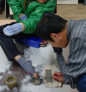 칠보 작품 제작을 위해 발로 붓질을 하는 장면. = 정수지 기자